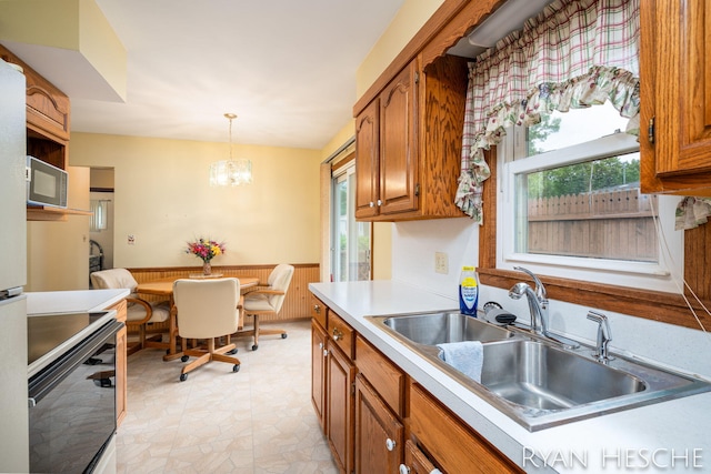4959 Havana Ave SW, Wyoming, MI 49509 - kitchen with white microwave, a sink, brown cabinets, range, and hanging light fixtures