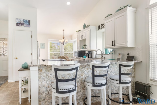 3361 English Hills Dr NW Unit 16, Grand Rapids, MI 49544 - kitchen with light stone counters, a sink, white cabinets, and a chandelier