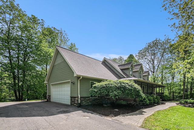 8315 Woodland Cir, Goodrich, MI 48438 - view of property exterior with a garage, driveway, a sunroom, stone siding, and roof with shingles