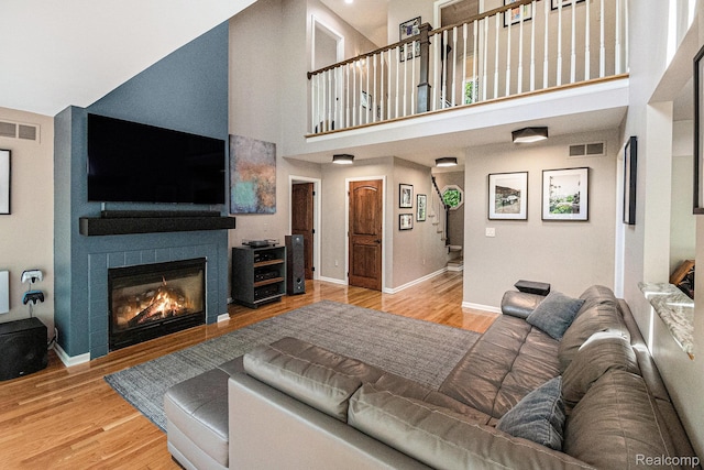 8315 Woodland Cir, Goodrich, MI 48438 - living room featuring wood finished floors, a high ceiling, a glass covered fireplace, and baseboards
