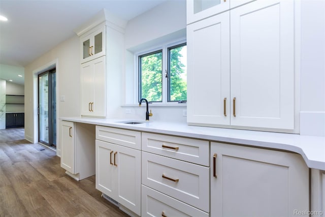 56259 Schoenherr Rd, Shelby Twp, MI 48315 - kitchen featuring a sink, wood finished floors, white cabinetry, glass insert cabinets, and light countertops