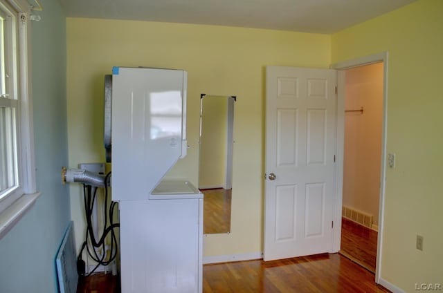 2683 Elmwood Dr, Adrian, MI 49221 - laundry area with stacked washer and clothes dryer, dark wood finished floors, and baseboards
