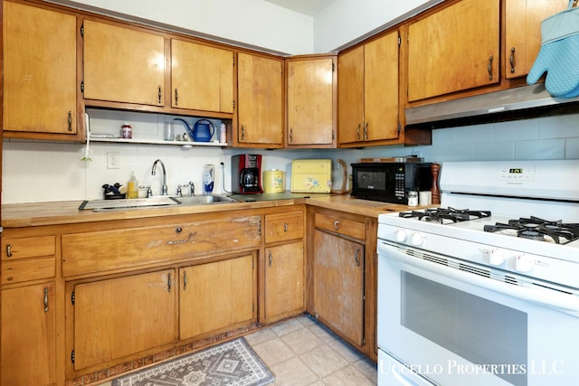 4505 E Apple Ave, Muskegon, MI 49442 - kitchen featuring white gas stove, black microwave, a sink, under cabinet range hood, and tasteful backsplash