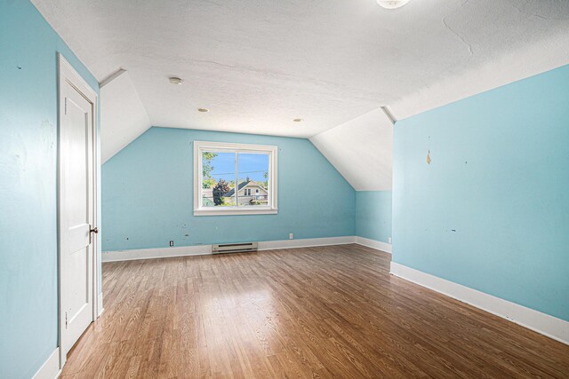 337 W 18th St, Holland, MI 49423 - additional living space featuring wood finished floors, baseboard heating, vaulted ceiling, a textured ceiling, and baseboards
