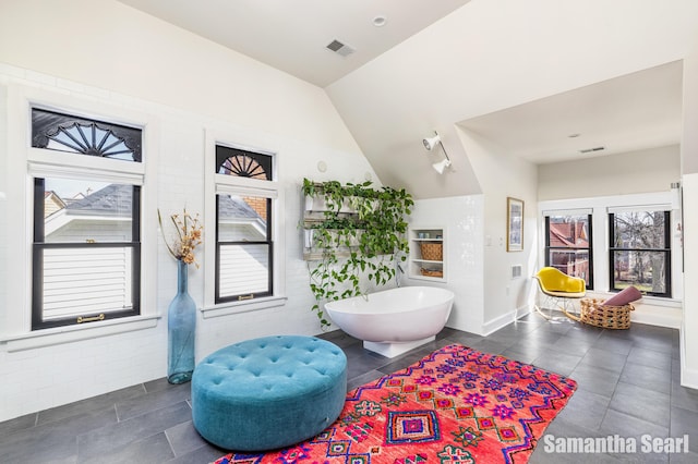 573 College Ave SE, Grand Rapids, MI 49503 - bathroom featuring a soaking tub, tile patterned floors, lofted ceiling, and baseboards