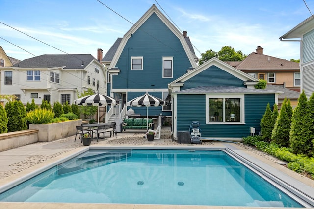 573 College Ave SE, Grand Rapids, MI 49503 - back of property with a patio area, a gambrel roof, and an outdoor pool