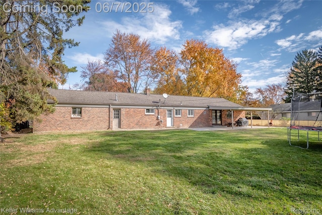 4879 Sundale Dr, Clarkston, MI 48346 - back of property with a trampoline, a patio area, brick siding, a yard, and french doors