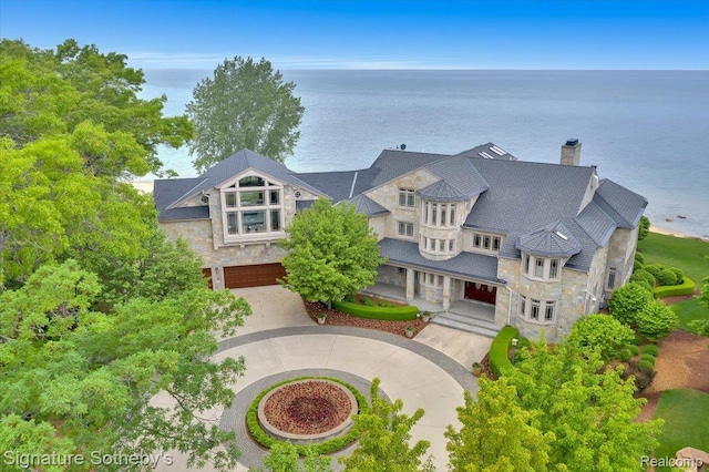 4150 Port Austin Rd, Caseville, MI 48725 - view of front of property with stone siding, curved driveway, an attached garage, a chimney, and a water view