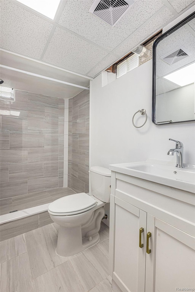 5239 E 13 Mile Rd, Warren, MI 48092 - bathroom featuring toilet, vanity, a tile shower, and a paneled ceiling