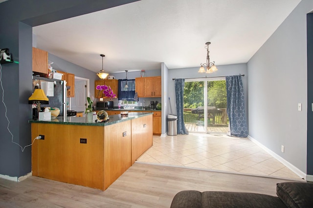 1417 Greenhouse Rd, Bangor, MI 49013 - kitchen featuring a peninsula, stainless steel appliances, dark countertops, decorative light fixtures, and baseboards