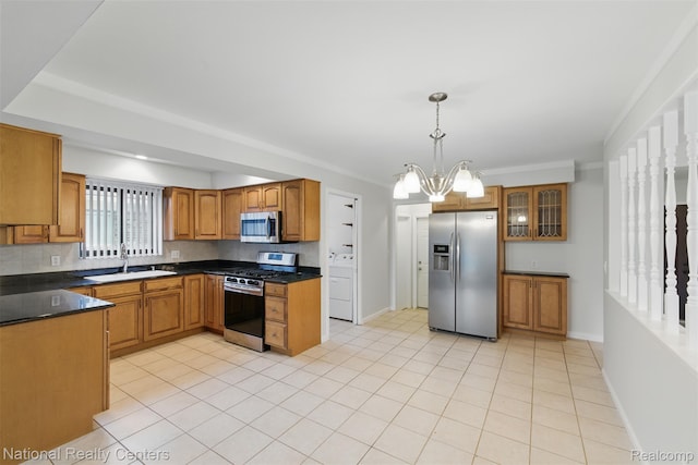 2430 Fox Hill Dr, Sterling Heights, MI 48310 - kitchen featuring appliances with stainless steel finishes, a sink, washer / clothes dryer, brown cabinets, and dark countertops