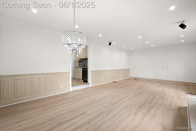 22923 Madison St, Dearborn, MI 48124 - empty room with a chandelier, light wood-type flooring, recessed lighting, and a wainscoted wall