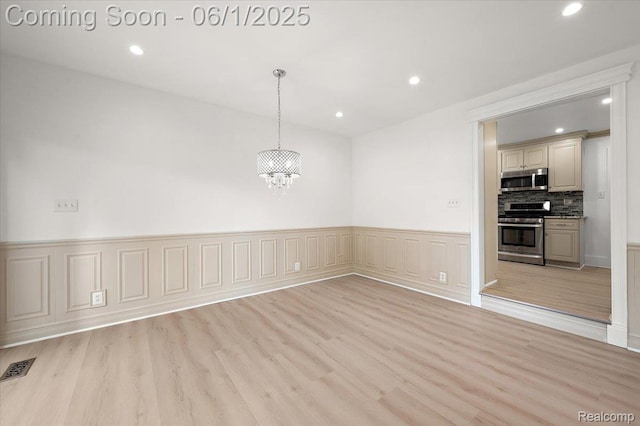 22923 Madison St, Dearborn, MI 48124 - empty room featuring a chandelier, light wood-style floors, recessed lighting, and a wainscoted wall