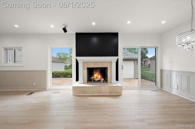 22923 Madison St, Dearborn, MI 48124 - unfurnished living room featuring healthy amount of natural light, a decorative wall, light wood finished floors, recessed lighting, and a tiled fireplace
