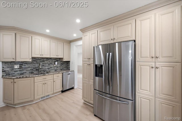 22923 Madison St, Dearborn, MI 48124 - kitchen featuring appliances with stainless steel finishes, cream cabinetry, a sink, backsplash, and light wood-style flooring
