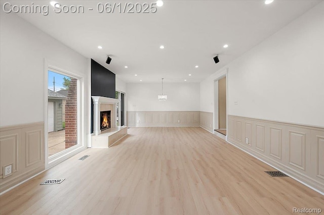 22923 Madison St, Dearborn, MI 48124 - unfurnished living room featuring a warm lit fireplace, a wainscoted wall, light wood-type flooring, recessed lighting, and a decorative wall