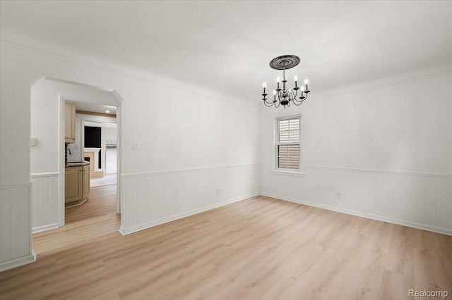 22923 Madison St, Dearborn, MI 48124 - unfurnished room with a chandelier, light wood finished floors, wainscoting, ornamental molding, and arched walkways