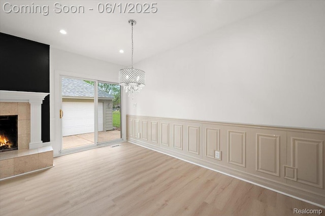 22923 Madison St, Dearborn, MI 48124 - unfurnished dining area with wood finished floors, a tiled fireplace, wainscoting, recessed lighting, and a chandelier