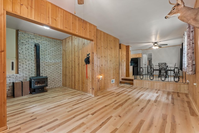 2240 S 13th St, Niles, MI 49120 - unfurnished living room with ceiling fan, wood finished floors, wood walls, a wood stove, and brick wall
