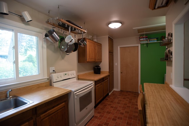1204 Bydding Rd, Ann Arbor, MI 48103 - kitchen featuring white range with electric stovetop, a sink, brown cabinetry, and wood counters