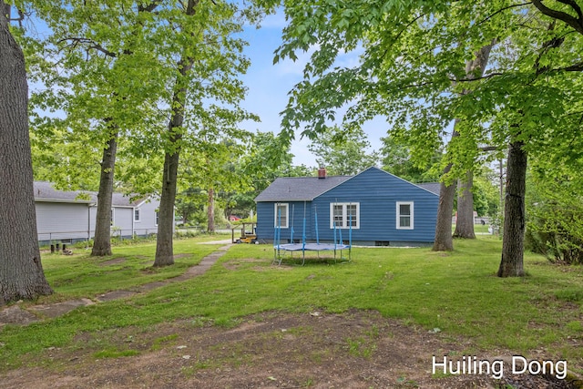 45 S Park St, Muskegon, MI 49442 - rear view of house with a lawn, a chimney, a trampoline, and a shingled roof