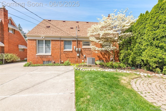 7639 Polk St, Taylor, MI 48180 - rear view of property with central AC unit, brick siding, a shingled roof, and a yard