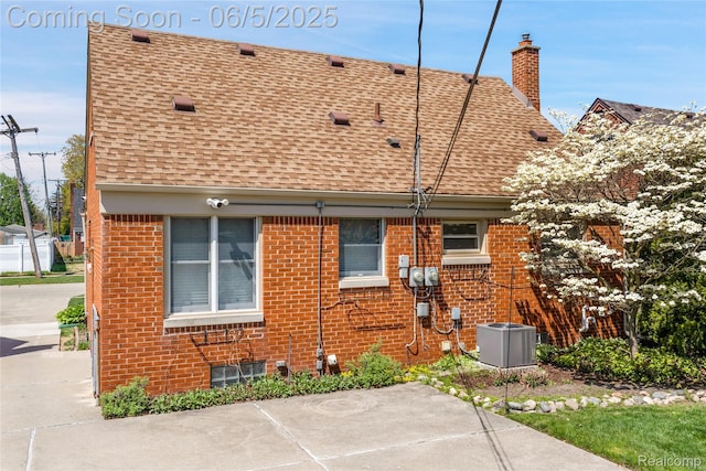 7639 Polk St, Taylor, MI 48180 - rear view of house with roof with shingles, central AC, a chimney, and brick siding