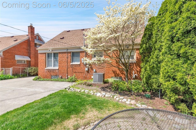 7639 Polk St, Taylor, MI 48180 - back of house featuring cooling unit, brick siding, roof with shingles, and a yard