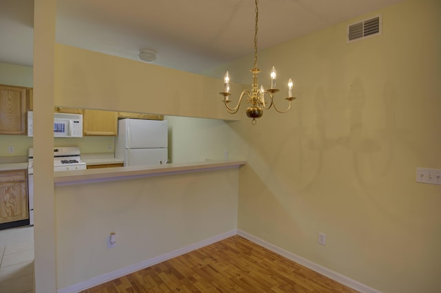 920 Oakbrook Dr, Jackson, MI 49203 - kitchen featuring white appliances, a chandelier, light countertops, a peninsula, and light wood-style flooring