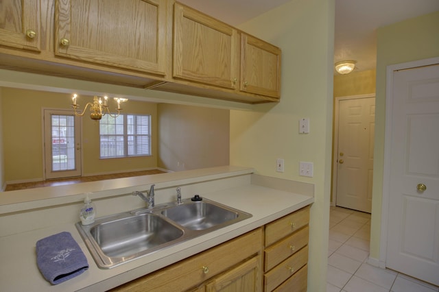 920 Oakbrook Dr, Jackson, MI 49203 - kitchen with a sink, light brown cabinetry, light tile patterned floors, light countertops, and a chandelier
