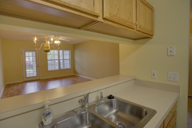 920 Oakbrook Dr, Jackson, MI 49203 - kitchen featuring light countertops, a chandelier, wood finished floors, a sink, and baseboards