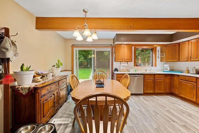 917 Kensington Dr, Niles, MI 49120 - kitchen with stainless steel dishwasher, beamed ceiling, light wood-type flooring, brown cabinets, and a chandelier
