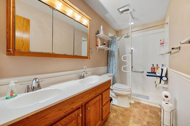 917 Kensington Dr, Niles, MI 49120 - full bathroom with a wainscoted wall, curtained shower, double vanity, and toilet