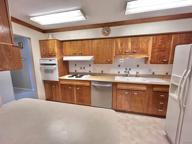 818 W Chestnut St, Morenci, MI 49256 - kitchen with white appliances, under cabinet range hood, brown cabinetry, backsplash, and a sink