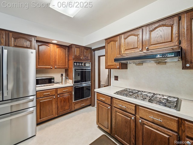 4677 Rolling Ridge Rd, West Bloomfield, MI 48323 - kitchen featuring appliances with stainless steel finishes, under cabinet range hood, light countertops, and brown cabinets