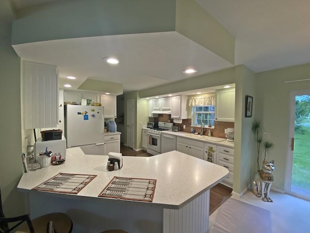 10439 Castaway Ct, Canadian Lakes, MI 49346 - kitchen featuring white appliances, a peninsula, light countertops, white cabinets, and baseboards