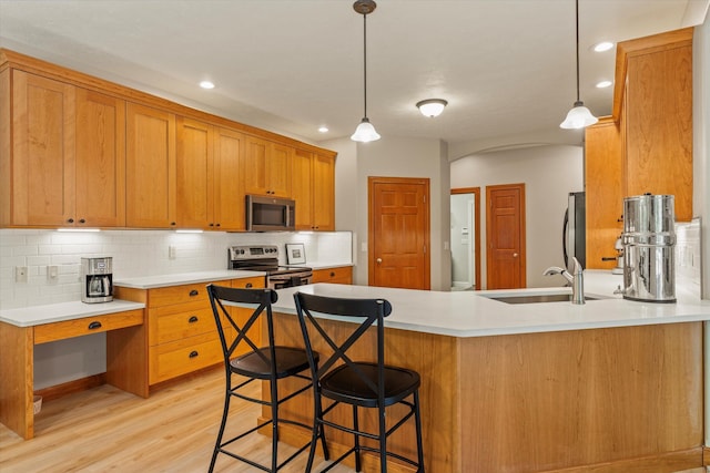 11082 Hoffman Rd, Marcellus, MI 49067 - kitchen with stainless steel appliances, a sink, a peninsula, tasteful backsplash, and light wood-style flooring