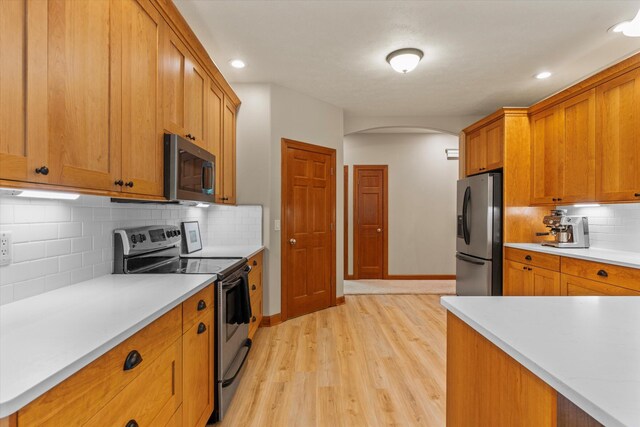 11082 Hoffman Rd, Marcellus, MI 49067 - kitchen featuring appliances with stainless steel finishes, arched walkways, light wood finished floors, light countertops, and recessed lighting
