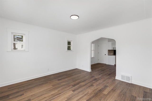 7505 E Robinwood St, Detroit, MI 48234 - empty room featuring arched walkways, dark wood-type flooring, and baseboards