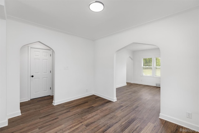 7505 E Robinwood St, Detroit, MI 48234 - unfurnished room featuring arched walkways, dark wood-type flooring, and baseboards