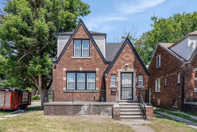 7505 E Robinwood St, Detroit, MI 48234 - tudor home featuring brick siding, a shingled roof, and a front lawn