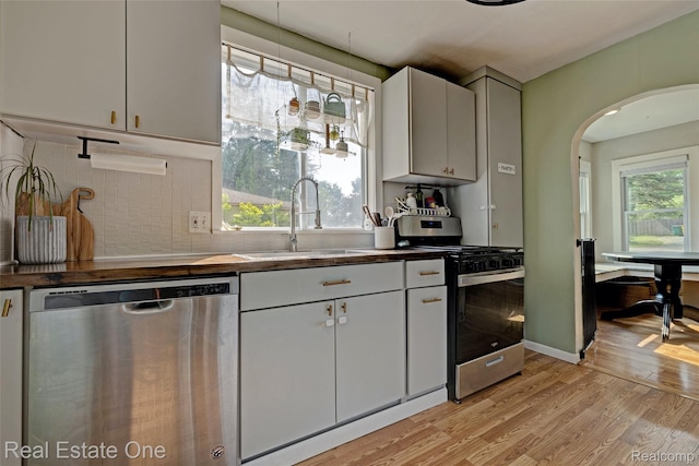 110 Minnetonka Dr, Oxford, MI 48371 - kitchen with appliances with stainless steel finishes, a sink, light wood-style floors, arched walkways, and tasteful backsplash