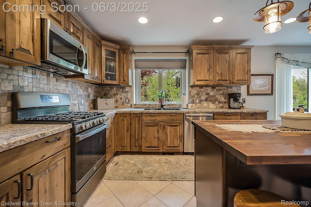 1355 Maxfield Rd, Brighton, MI 48114 - kitchen with appliances with stainless steel finishes, wooden counters, a sink, light tile patterned floors, and backsplash