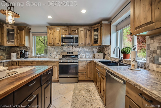 1355 Maxfield Rd, Brighton, MI 48114 - kitchen featuring appliances with stainless steel finishes, a sink, butcher block countertops, decorative backsplash, and glass insert cabinets