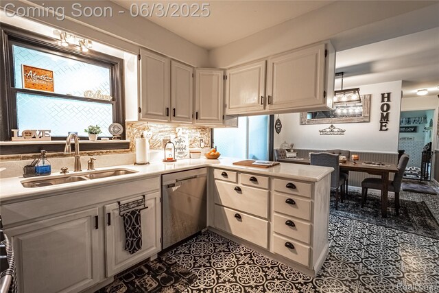 527 Montana St, Marysville, MI 48040 - kitchen with stainless steel dishwasher, a sink, light countertops, a peninsula, and white cabinetry