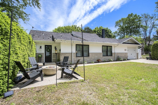 121 S Barker St, New Buffalo, MI 49117 - view of front facade featuring a fire pit, a front lawn, concrete driveway, board and batten siding, and an attached garage