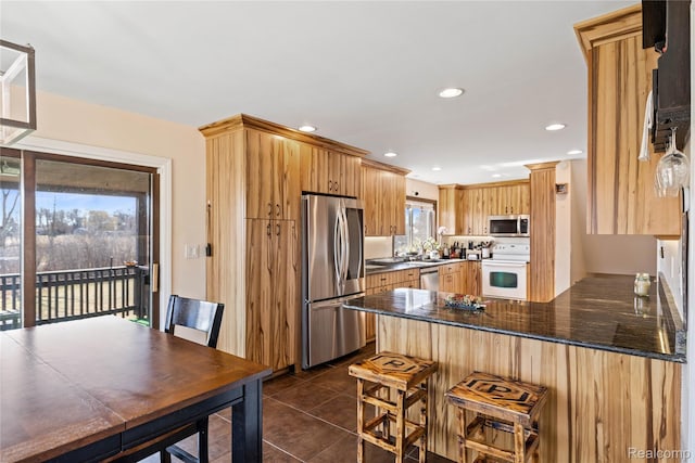254 Cross Timbers St, Oxford, MI 48371 - kitchen with appliances with stainless steel finishes, a peninsula, dark tile patterned floors, recessed lighting, and dark stone counters