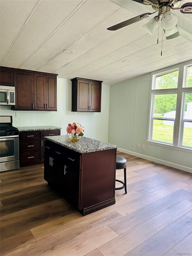 10365 Alans Dr, Fowlerville, MI 48836 - kitchen with appliances with stainless steel finishes, wood finished floors, a ceiling fan, stone counters, and a textured ceiling