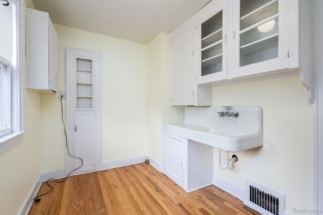 17173 New York St, Detroit, MI 48224 - laundry area featuring baseboards, light wood-style floors, and a sink