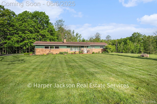 2210 Brookhaven Dr, Flint, MI 48507 - view of front of home featuring a chimney, a front yard, brick siding, and a forest view